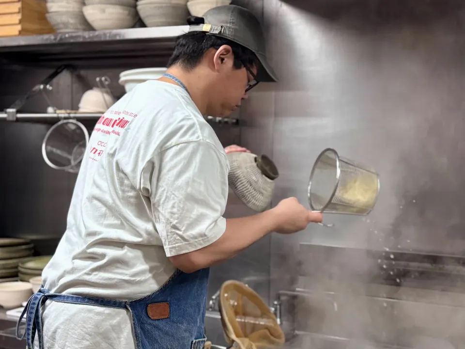 湯気の立つ釜から麺を上げる